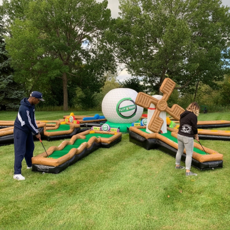 Two people playing mini golf on a large circular inflatable course with large golf ball in the middle.