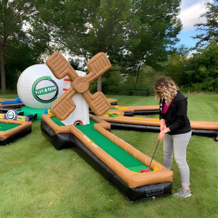 Inflatable mini golf course rental with a woman playing on a grassy field during an event in Rochester, NY.