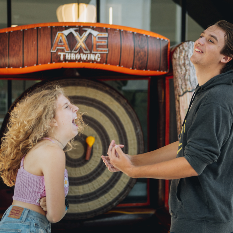 Two players laughing while playing the Inflatable Axe Throwing Game Rental in Rochester, NY