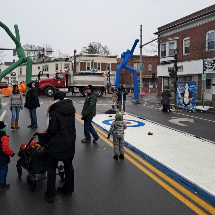 People playing curling on a rented rink at a Winter Street Festival in Upstate New York.