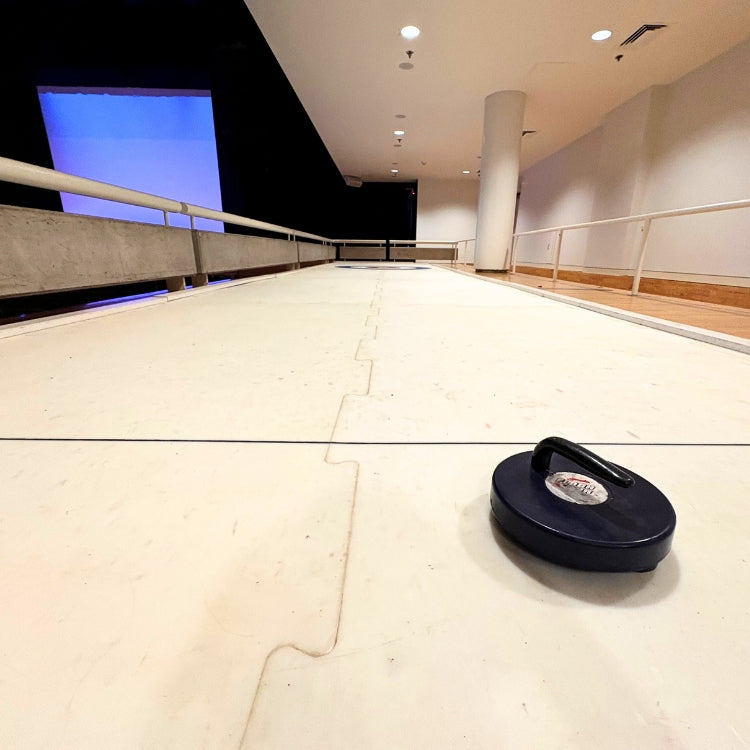 Rock sitting on a synthetic ice curling rink rental before an indoor college event begins in Syracuse, New York.