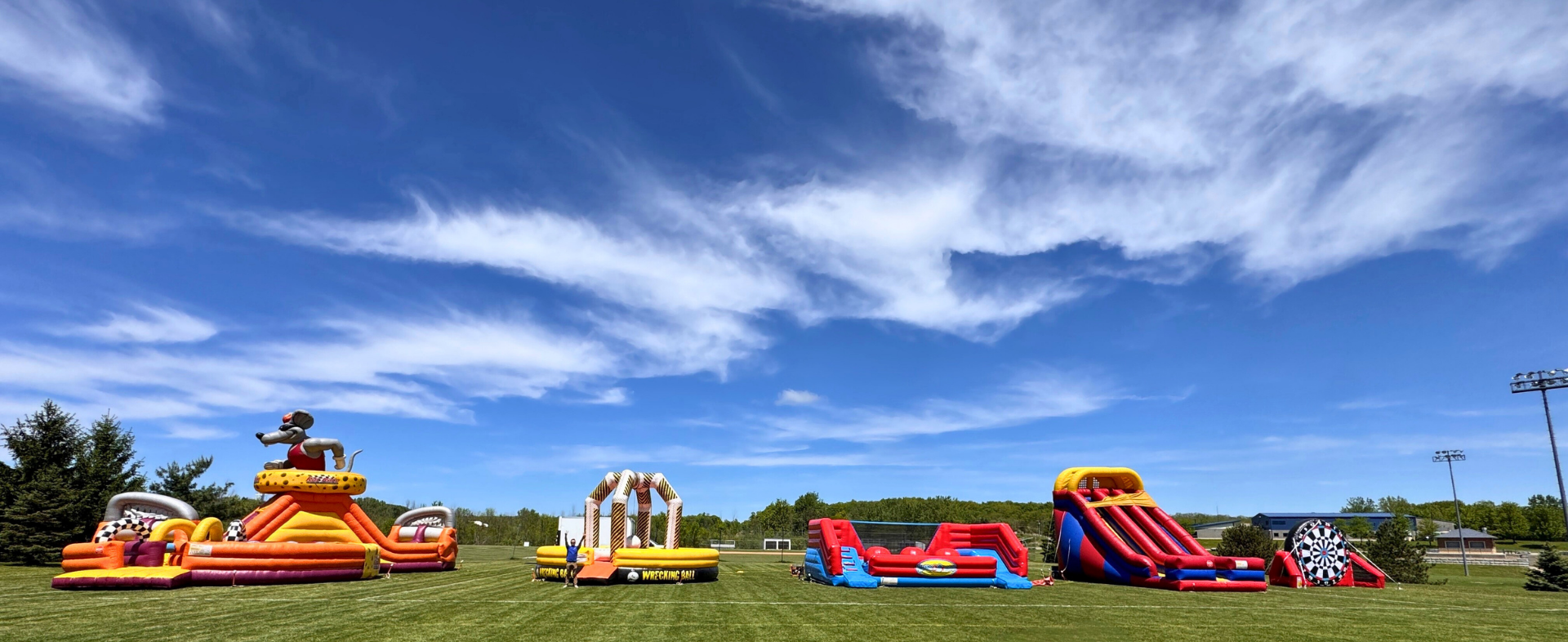 Multiple Inflatable Attractions Setup for an Outdoor Event in Rochester, NY on a Sunny Day
