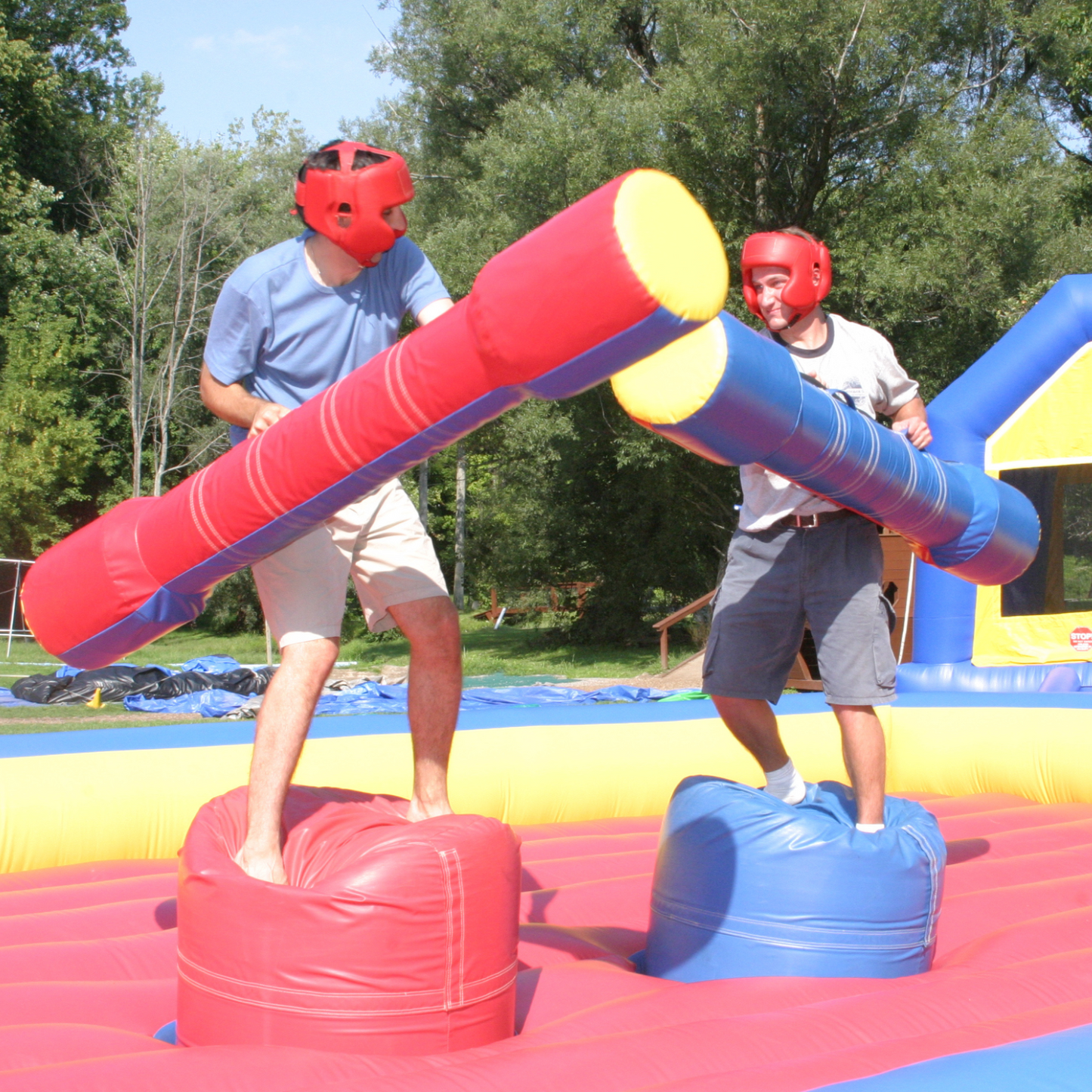 Up close image of the Gladiator Jousting inflatable rental with two players battling it out while holding foam jousting poles and protective headgear