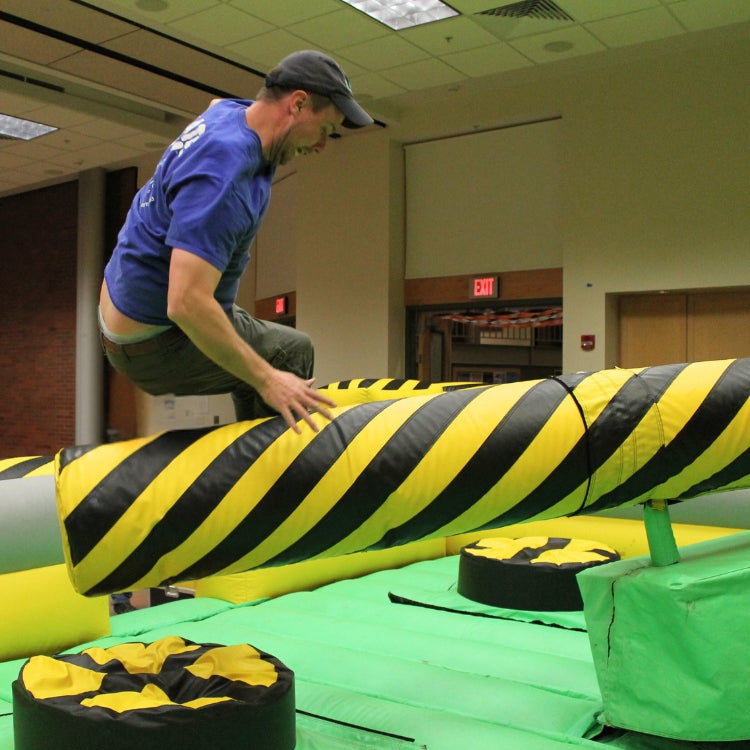 Man Having Fun Jumping Over the Mechanical Arm on the Meltdown Zone Inflatable Rental at Event in Rochester, NY